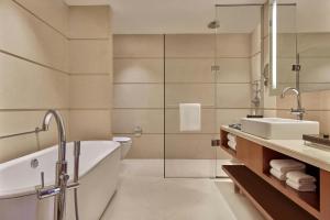 a bathroom with a tub and a sink and a toilet at Courtyard by Marriott Kochi Airport in Nedumbassery