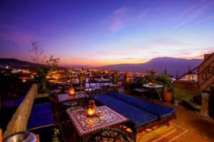 a rooftop patio with tables and chairs at night at Riad Bab Mahrouk in Chefchaouene
