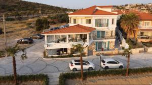 two cars parked in a parking lot in front of a house at Alesya Otel in Çiftlikköyü