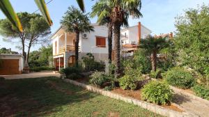 a house with palm trees in front of a yard at One-Bedroom Apartment Malinska near Sea 2 in Malinska