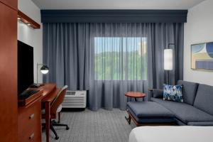 a hotel room with a couch and a desk and a window at Courtyard Pittsburgh Settlers Ridge/Robinson Township in Robinson Township