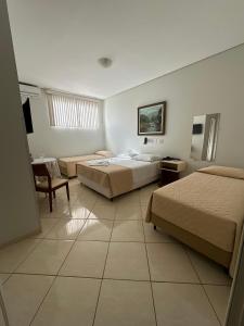a hotel room with two beds and a table at Aruanã Palace Hotel in Colíder