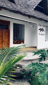 a building with a door and a palm tree at Palm House&Restaurant in Utende