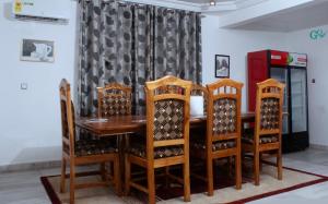 a dining room with a wooden table and chairs at CARL's VILLA APARTMENTS in Accra