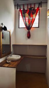 a bathroom with a sink and a window with a curtain at Palm House&Restaurant in Utende