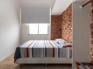 Un dormitorio con una cama y una pared de ladrillo. en Apartamento com Ar-Condicionado, en Salvador