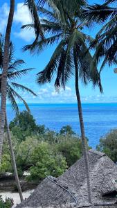 a view of the ocean from a beach with two palm trees at Palm House&Restaurant in Utende