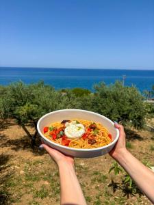 a person holding up a bowl of spaghetti and eggs at La Finestra Sul Mare in Tusa +19 photos