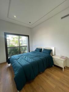 a bedroom with a large blue bed and a window at Appartement Luxe Vue Piscine Résidence Les Perles de Bentriaa, El Mansouria in Mohammedia +9 photos
