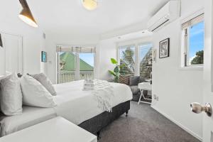 a white bedroom with a bed and a couch at Charming 2BR Home Near City & Bay by Zodiak Stays in Auckland
