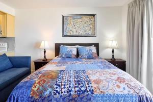 a bedroom with a bed and a blue couch at Ground Floor Condo - Ocean View - Pool & Hot Tub in Lincoln City