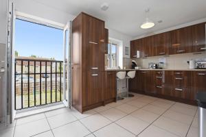 cocina con armarios de madera y balcón en Modern 5BR Stay for Work & Groups, en Watford