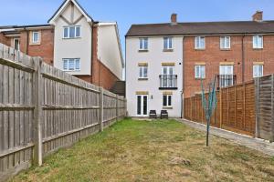 Una valla en un patio junto a unos edificios. en Modern 5BR Stay for Work & Groups, en Watford