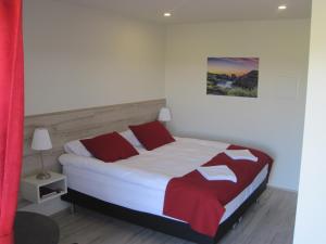 a bedroom with a bed with red and white pillows at Skógar Sunset Guesthouse in Húsavík