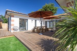 a wooden deck with a table and an umbrella at Villa vacances Bassin d'Arcachon in Gujan-Mestras