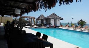 a swimming pool with chairs and the ocean in the background at Las cabañas de Bonanza in Zorritos
