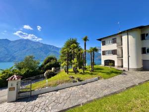 a building with palm trees next to a body of water at Villa Miralago in Tronzano Lago Maggiore
