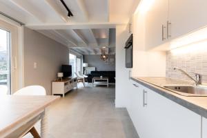 eine Küche mit weißen Schränken und ein Wohnzimmer in der Unterkunft Boszicht Huisje 32 in Nieuwmunster
