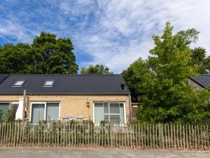 ein Haus mit einem schwarzen Dach und einem Zaun in der Unterkunft Boszicht Huisje 32 in Nieuwmunster
