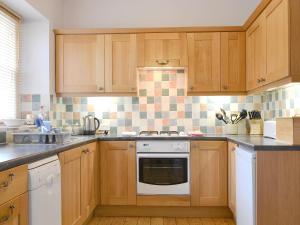 a kitchen with wooden cabinets and a stove top oven at Shorley Lodge in Keswick