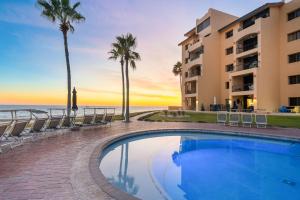 a resort pool with chairs and palm trees and the ocean at Princesa 3BR 2BA OV Penthouse- 502D in Campo del Medio