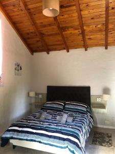 a bed in a bedroom with a wooden ceiling at Tu Casa en la Naturaleza in San Carlos de Bariloche