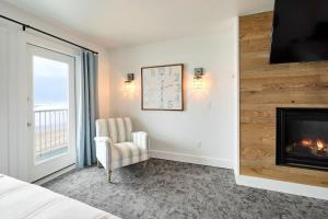 a bedroom with a fireplace and a chair and a window at Deluxe Suite for 6 King Bed & Ocean Views Pool and Hot Tub in Lincoln City