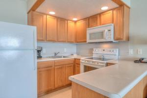 eine Küche mit Holzschränken und einem weißen Kühlschrank in der Unterkunft Stunning Ocean View Suite - Heated Indoor Pool and Hot Tub in Lincoln City