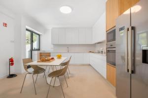 リベイラ・ブラーヴァにあるAtlantic Pebble Villaのテーブルと椅子と冷蔵庫のあるキッチン