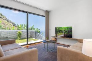 リベイラ・ブラーヴァにあるAtlantic Pebble Villaのテレビと大きな窓のあるリビングルーム