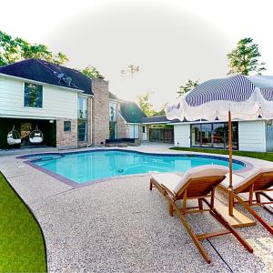 a swimming pool with two chairs and an umbrella at Lux Family Stay with Heated Pool, Spa, Theater, Game Room in Spring