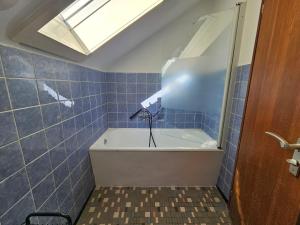 a blue tiled bathroom with a bath tub and a skylight at Monteurwohnung - Business Apartment in Wertheim