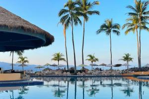 a resort swimming pool with palm trees and chairs at Spacious, standard with beach access & wifi! in Puerto Vallarta