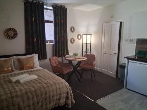 a bedroom with a bed and a table with chairs at Crown House Studio Apartment in Birmingham