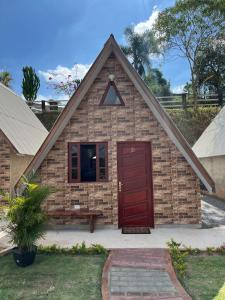 a small brick building with a red door at Chalés Paraíso Guararema 4 in Guararema +10 photos
