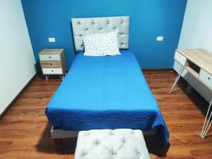 a blue bedroom with a bed with a blue bedspread at Pieza Amoblada 2 in Calama