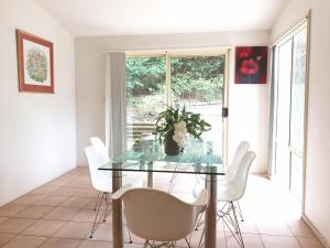 a dining room with a glass table and white chairs at Terrigal beach heaven secne in Terrigal