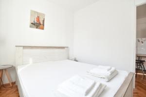 a white bed in a white room with towels on it at Stone & Sea in Budva