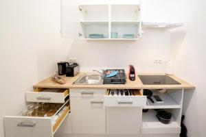 a white kitchen with a sink and a counter at Premium Cosy Apartment with Free Parking in Vienna +20 photos