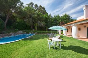 a backyard with a pool and a table and umbrella at Very Quiet Place in Sintra