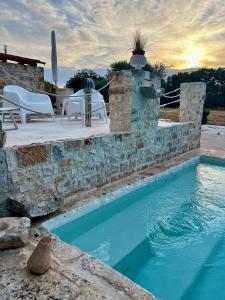 a pool with a stone wall and chairs and a table at Trullincanto Monopoli by JD Collection in Monopoli