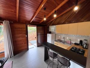 a kitchen with a black counter top and wooden ceilings at Emma Cabana Chalé Blumenau in Blumenau