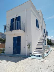 a white building with blue doors and stairs on it at Un Posto Al Sole in San Vito lo Capo