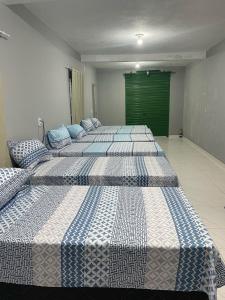 three beds in a room with a green door at Hostel do Porto in Queimada