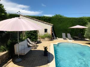 an umbrella and chairs next to a swimming pool at Gite La Bastide De La Coda in Châteauneuf-du-Rhône