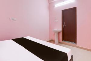 a bedroom with a bed and a sink and a door at Hotel O SK in Sītāpur +21 photos
