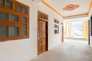 an empty corridor with wooden doors and windows at Hotel O SK in Sītāpur