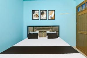 a blue room with a bed with three pictures on the wall at Hotel O SK in Sītāpur
