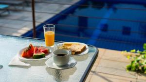 a tray with a plate of fruit and a glass of orange juice at Hotel do Sol Executive in São Sebastião