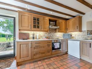 a kitchen with wooden cabinets and white appliances at Rhandir Barn in Ffair-fâch